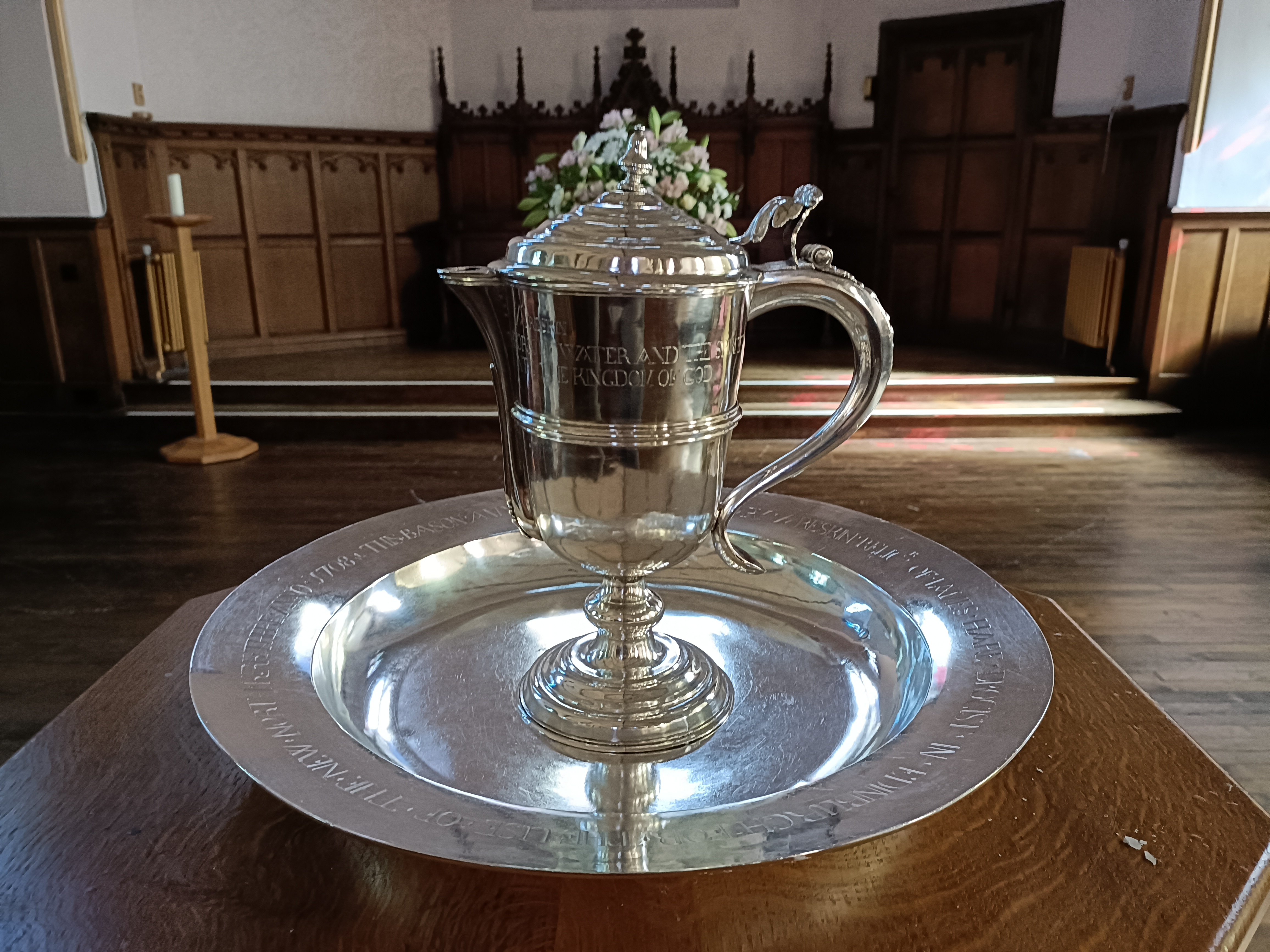 The silver laver and basin sitting on a wooden pedestal in the church.